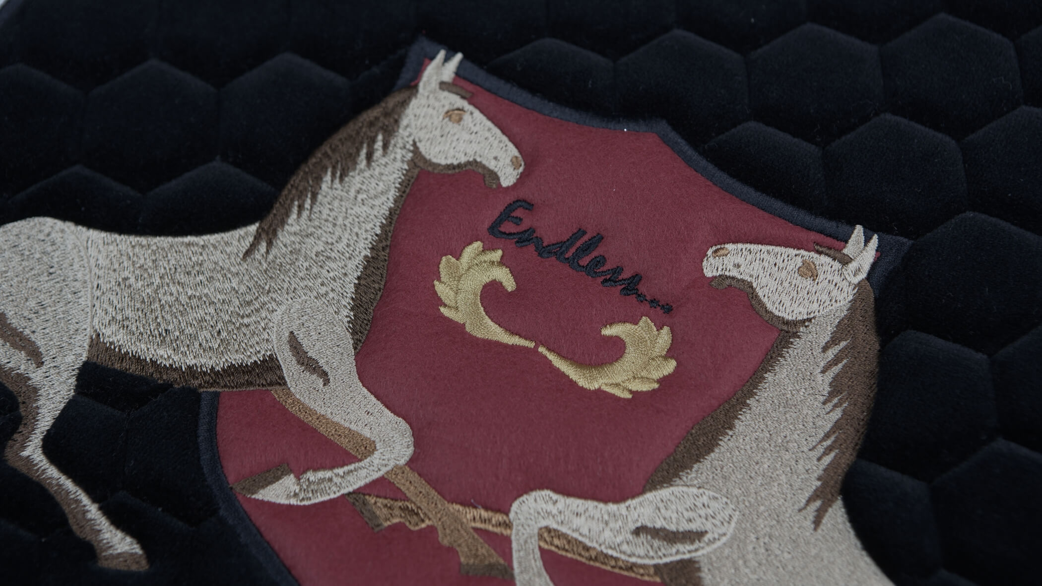 Detalhe de bordado acolchoado em que se podem observar outras técnicas de bordados formando dois cavalos