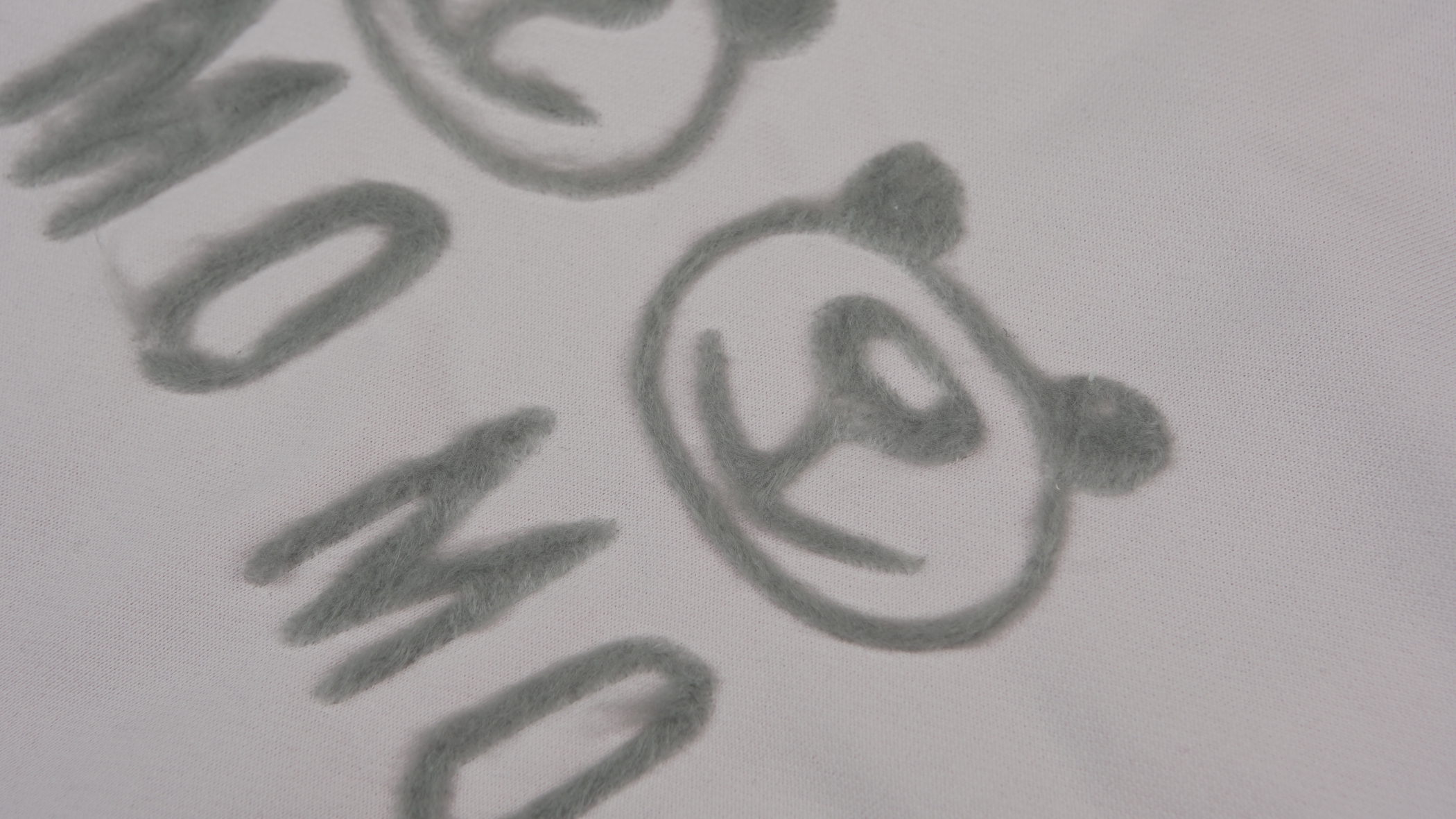 contorno de desenho de um urso com a palavra MOMO utilizando Bordado em TanaKa/Tanaka 3D