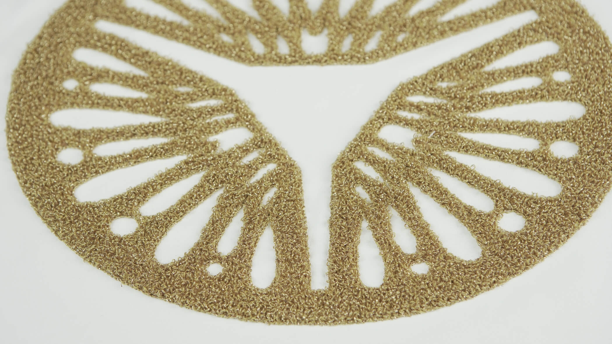 Detalhe de bordado ponto alto, chenille, em dourado, num tecido branco