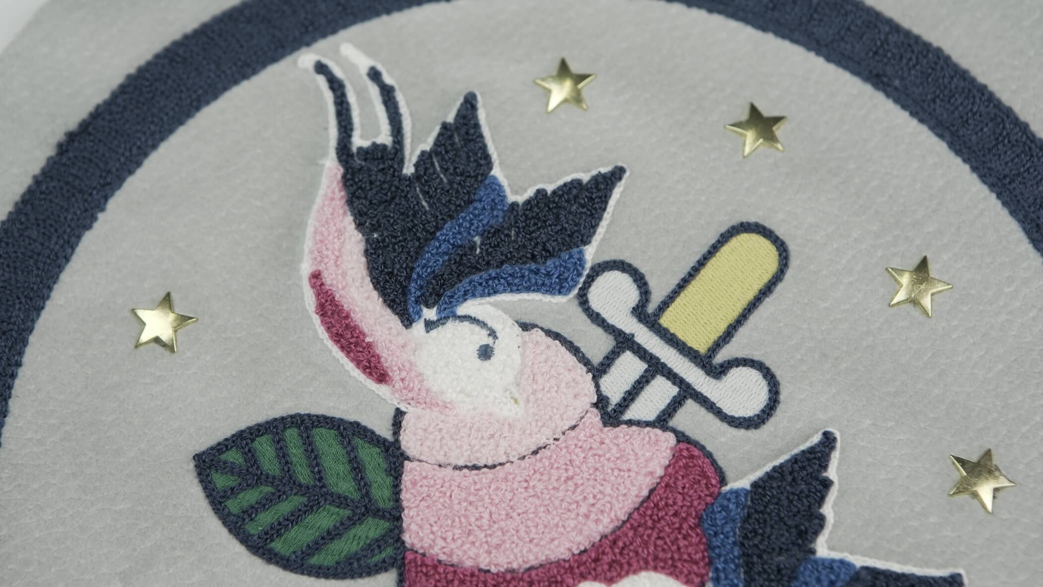Bordado de Ponto Alto - Chenille com um desenho onde se vê uma adaga espetada num coração, um pássaro e uma folha de árvore ou planta