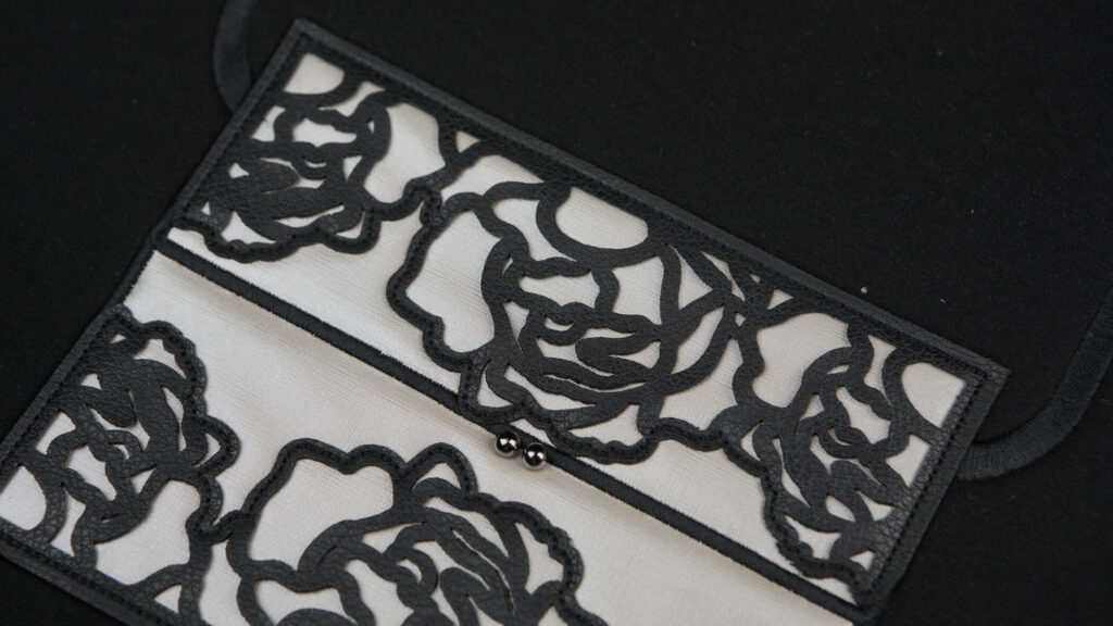 Bordados com aplicação em preto sobre fundo branco que formam uma espécie de flor semelhante a uma rosa