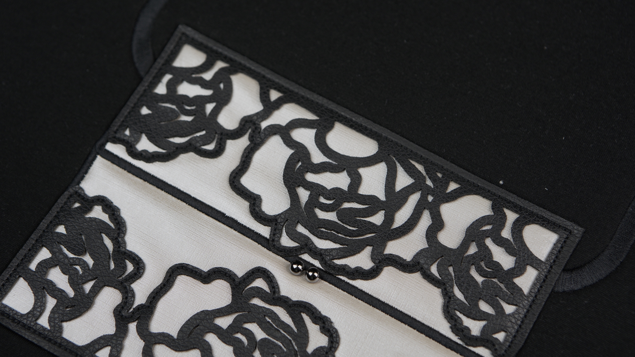 Bordados com aplicação em preto sobre fundo branco que formam uma espécie de desenho semelhante a uma rosa
